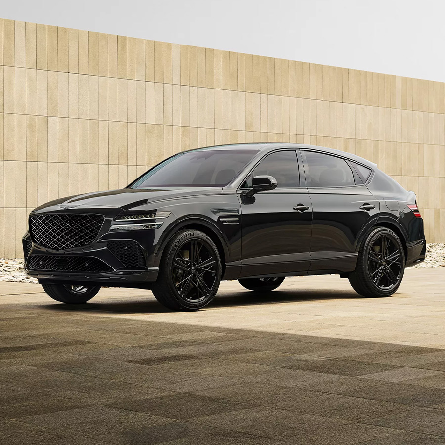 3/4 front driver side view of Genesis GV80 Coupe Prestige Black parked next to beige stone wall
