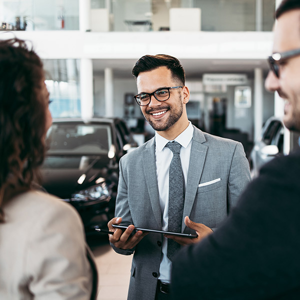 Happy car salesman talking with customers