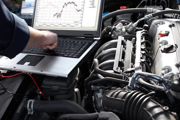 Close up of laptop running diagnostics under hood of car