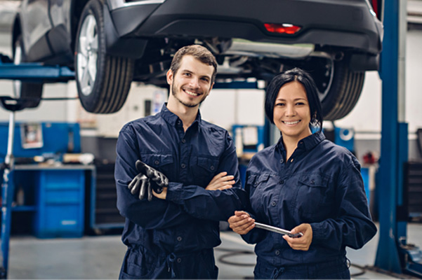 Female and male mechanic posing in autobody shop